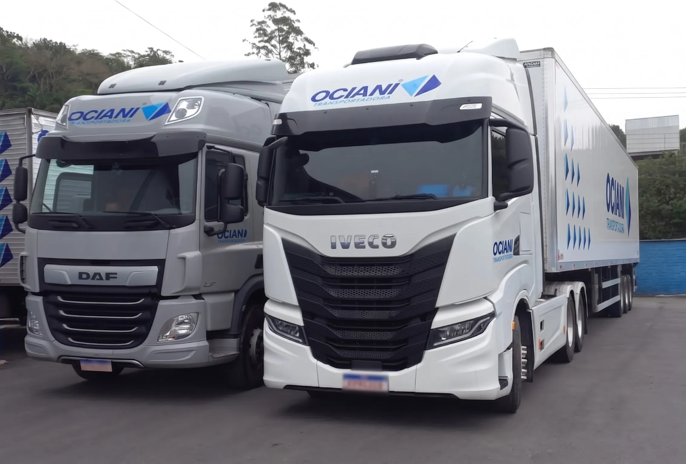 Caminhão DAF prata e cavalo Iveco S-Way branco da Ociani lado a lado, com carreta baú
