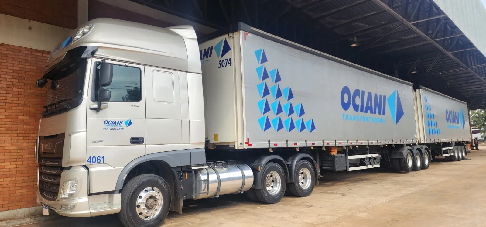 Cavalo DAF XF da Ociani puxando duas carretas sider com a marca, na doca do armazém